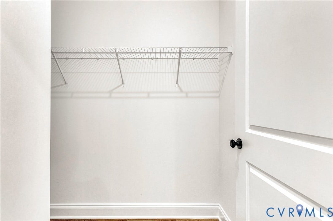 Spacious closet featuring wire shelving system with multiple tiers for organized storage, wood-finish flooring, and clean white walls with ample natural light from transom window