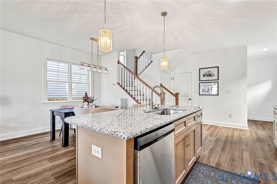 Kitchen island with a granite countertop, undermount sink, and stainless steel dishwasher