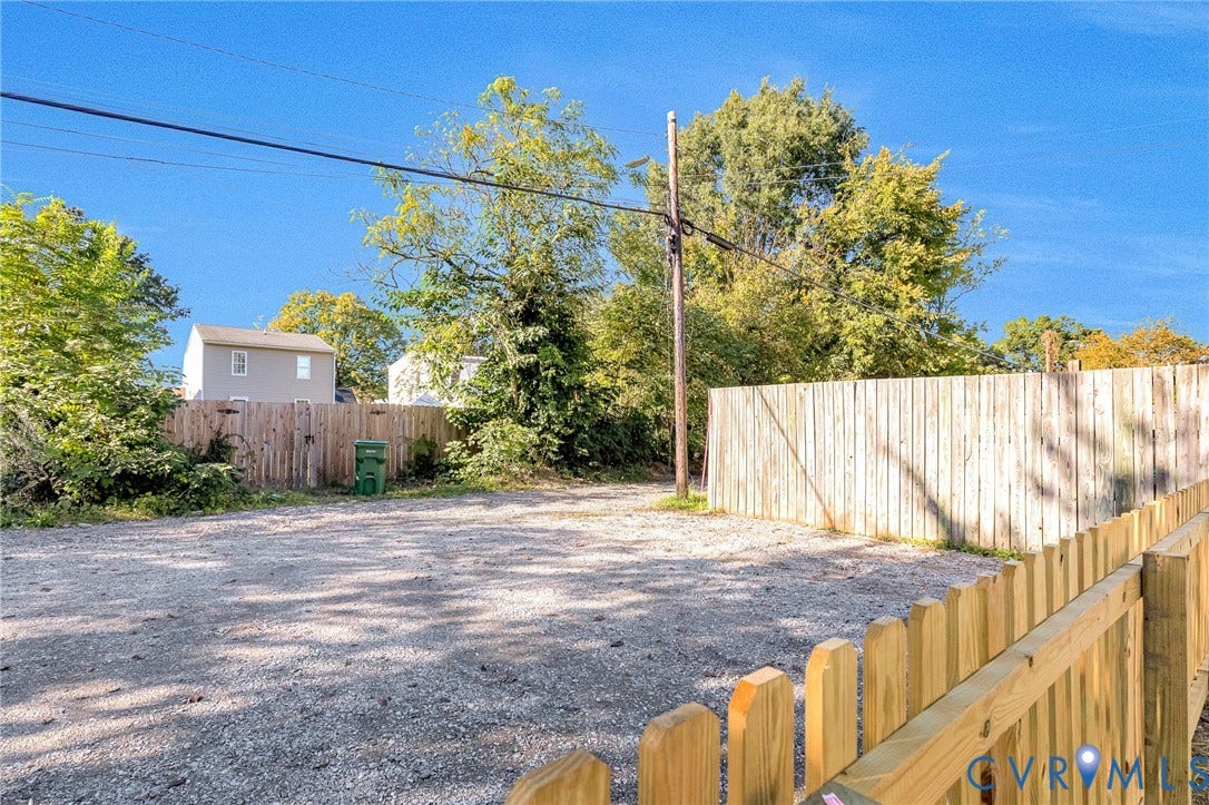 Spacious gravel lot with mature landscaping and established trees providing natural screening