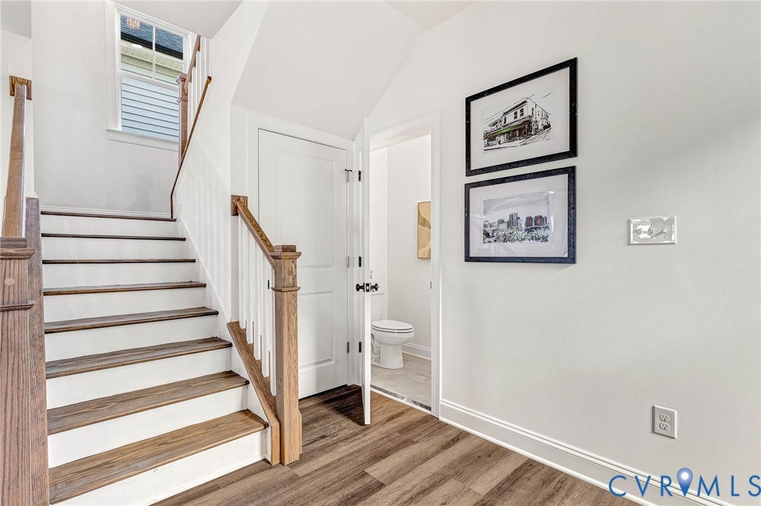 Staircase featuring wood-finish treads and white risers, complemented by a wood-finish handrail and newel posts