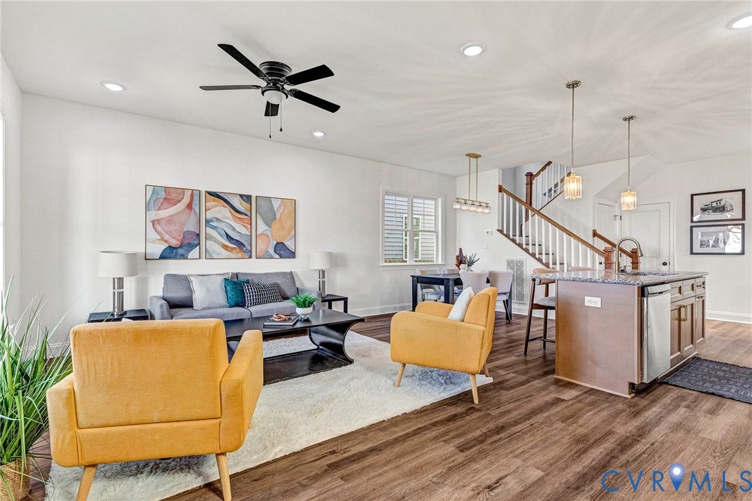 Wood-finish flooring throughout, recessed lighting, and a kitchen island with seating