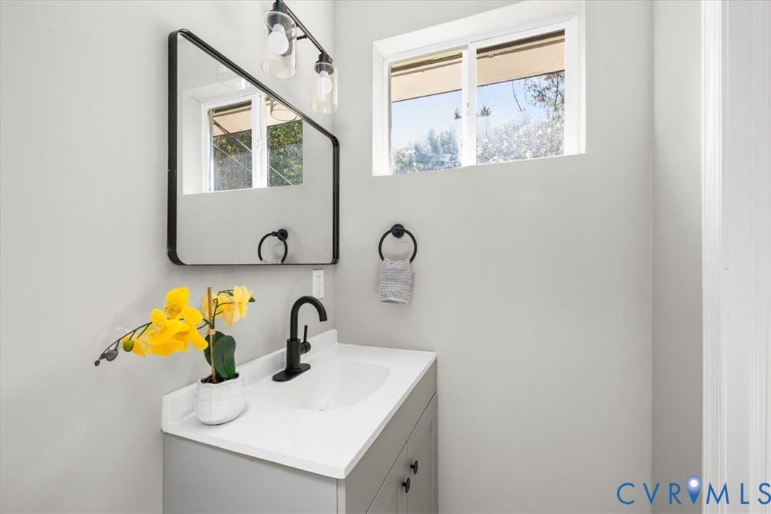 Bathroom vanity with a white countertop, integrated sink, and matte black faucet