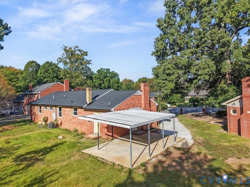 Brick exterior with multiple chimneys, featuring a covered patio and a detached brick structure