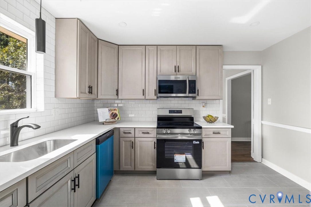Modern kitchen featuring stainless steel appliances, light wood-finish cabinetry, subway tile backsplash, and light-toned countertops