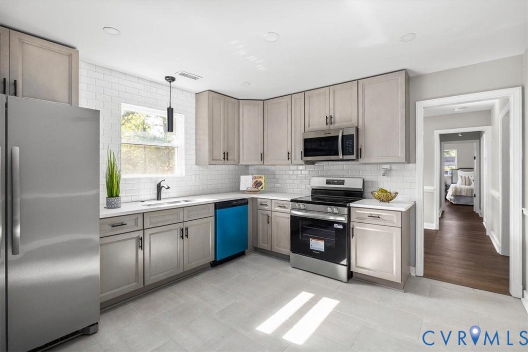 White subway tile backsplash, stainless steel appliances, light gray cabinetry with dark hardware, white countertops, and light tile flooring