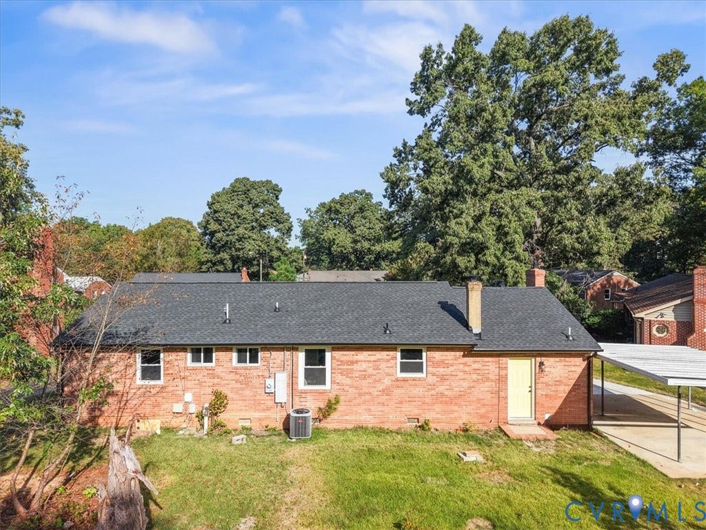 Brick exterior with a dark shingle roof, chimney, and a covered carport