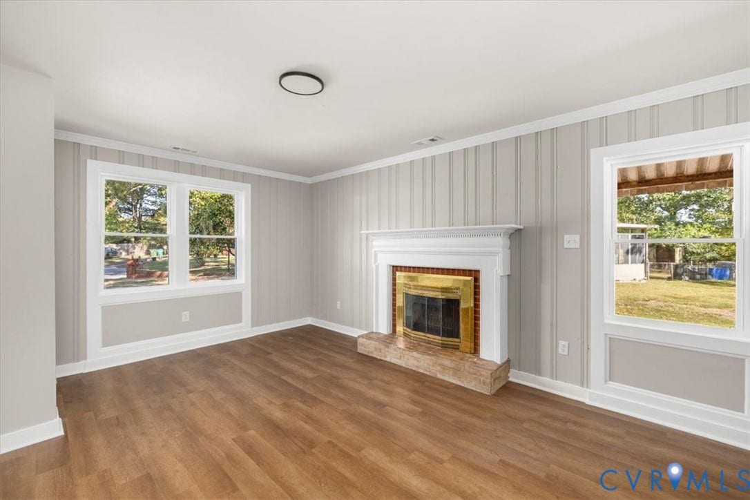 Wood-finish flooring throughout, featuring a fireplace with a brass-finish insert and stone hearth