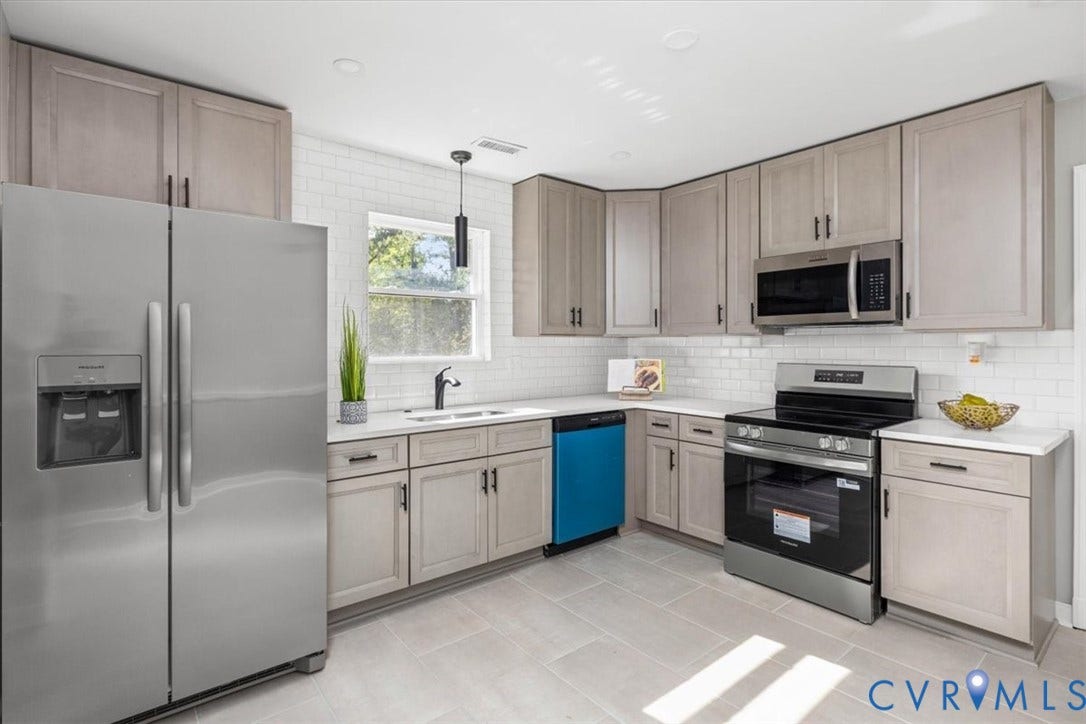 Kitchen featuring stainless steel appliances, light-toned cabinetry, white subway tile backsplash, light-colored countertops, and tiled flooring