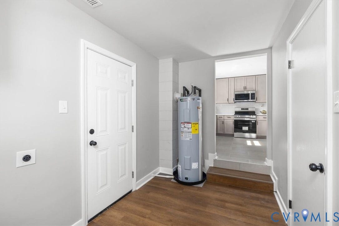 Wood-finish flooring with a white six-panel door and matte black hardware