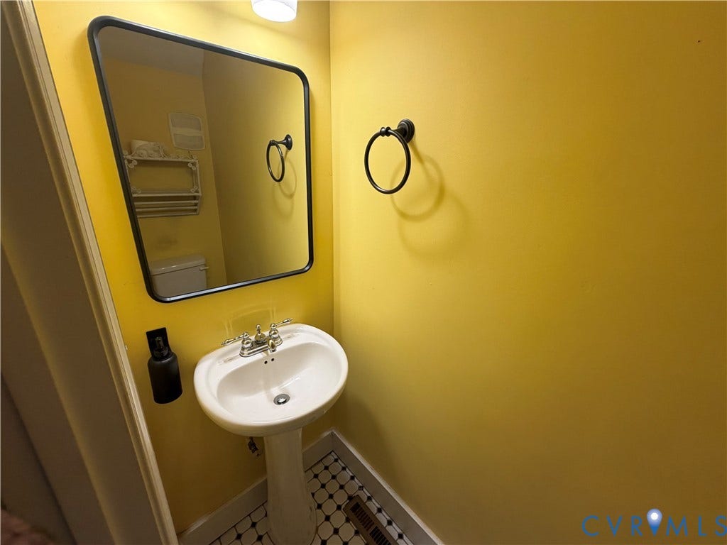 315 Grove Avenue, Petersburg, VA 23803 Pedestal sink, black-framed mirror, mosaic tile flooring, and wall-mounted towel ring