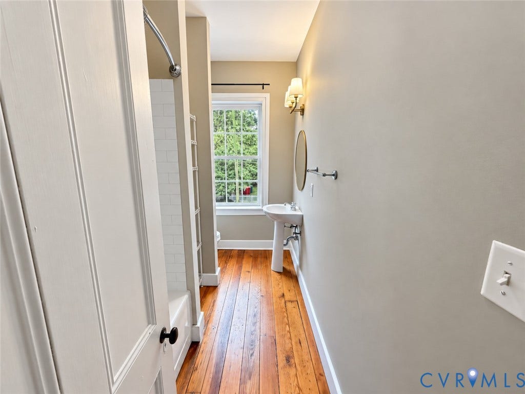 315 Grove Avenue, Petersburg, VA 23803 Hardwood flooring, pedestal sink, wall-mounted mirror, and white subway tile shower surround