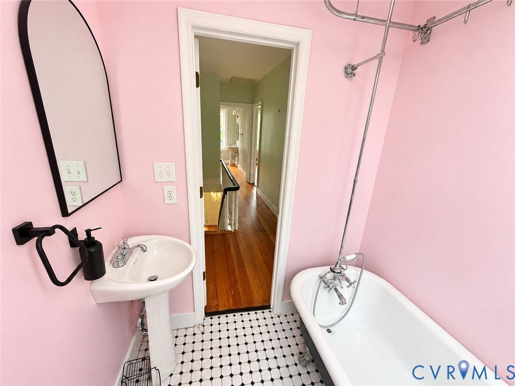 315 Grove Avenue, Petersburg, VA 23803 Pedestal sink with chrome faucet, black-framed arched mirror, clawfoot tub with shower attachment, and black and white mosaic tile flooring