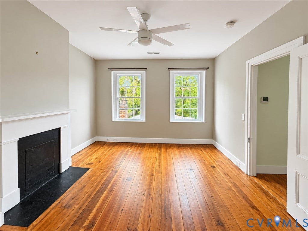 315 Grove Avenue, Petersburg, VA 23803 Hardwood flooring, white trim, recessed fireplace with dark hearth, two double-hung windows, and a ceiling fan