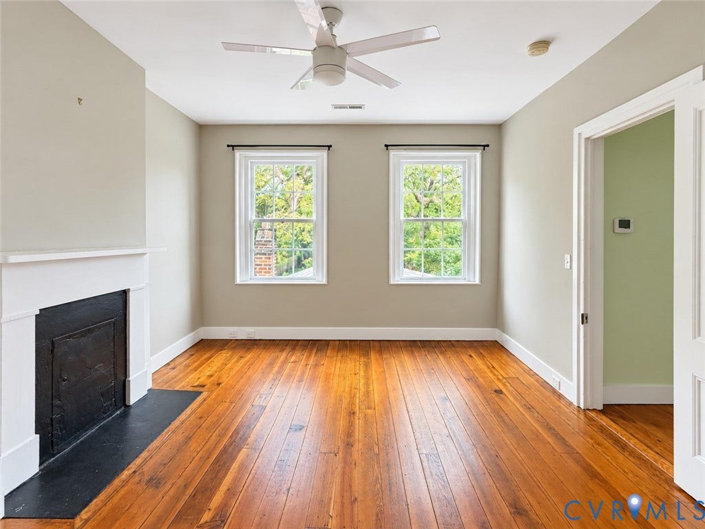 315 Grove Avenue, Petersburg, VA 23803 Wood-finish flooring, white trim, two double-hung windows, ceiling fan, and a fireplace with a black hearth