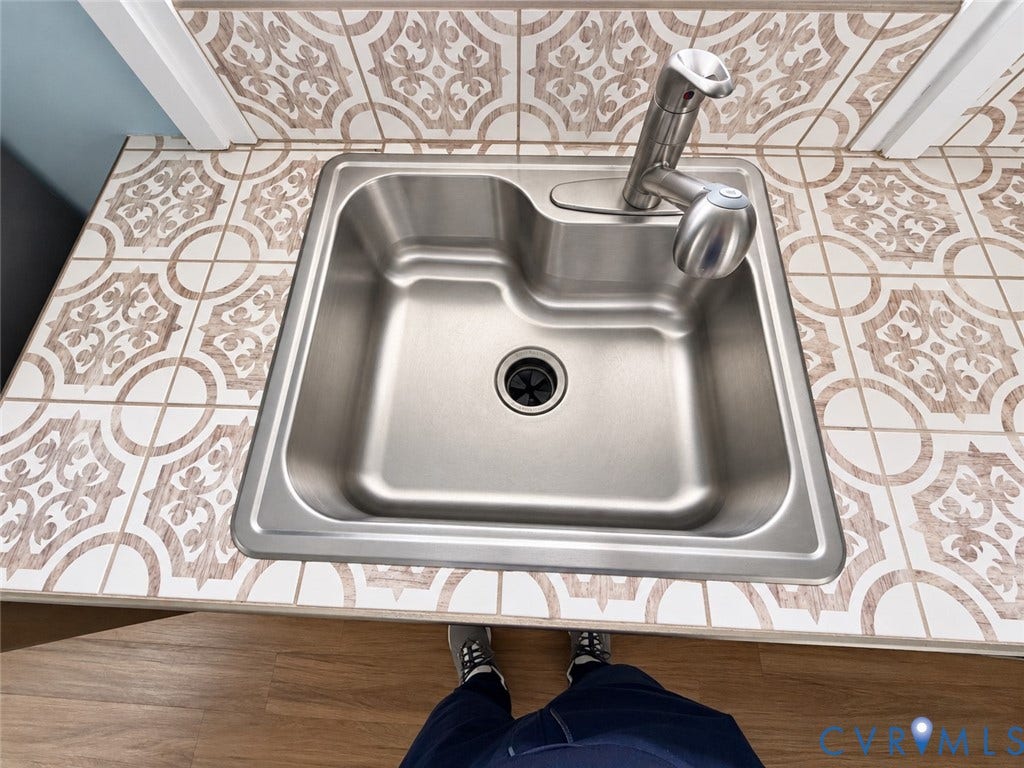 315 Grove Avenue, Petersburg, VA 23803 Stainless steel sink with a single-handle faucet, set into a tiled countertop featuring a decorative pattern