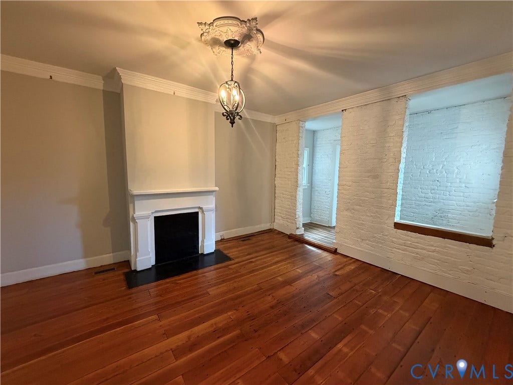 315 Grove Avenue, Petersburg, VA 23803 Hardwood flooring, painted brick wall, fireplace with white mantel, decorative ceiling medallion, and suspended light fixture