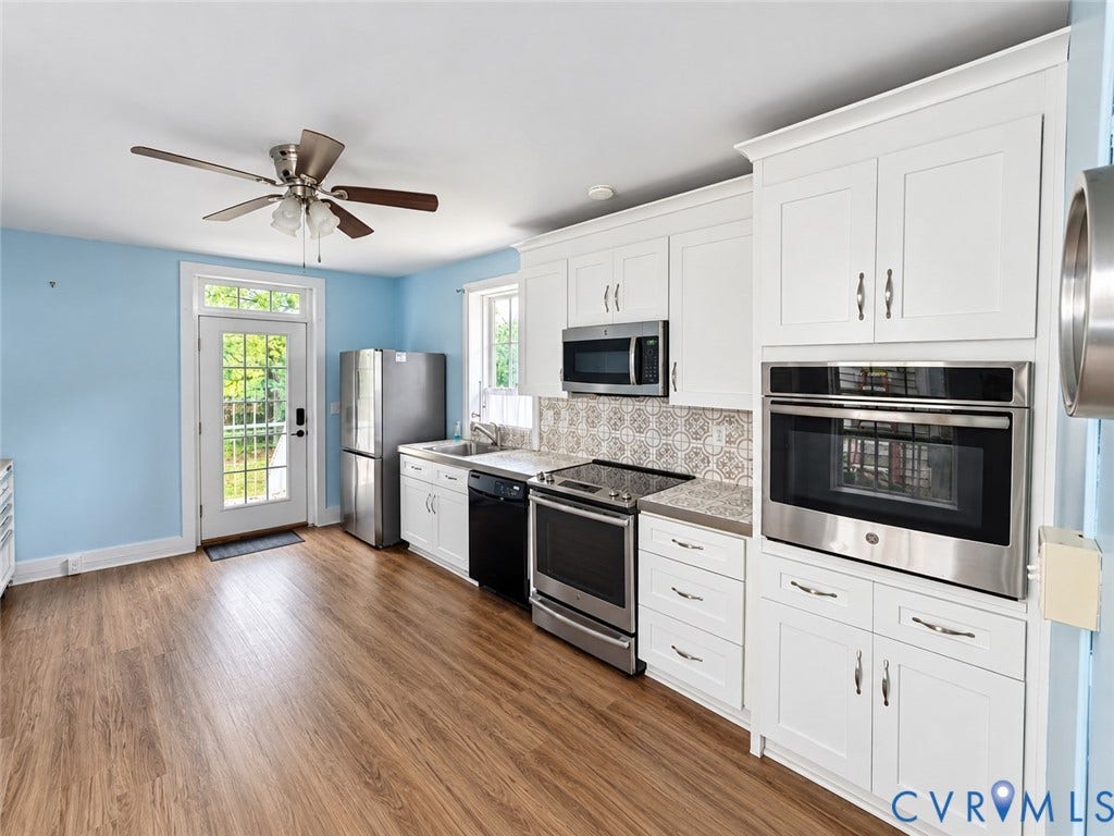 315 Grove Avenue, Petersburg, VA 23803 Kitchen featuring white shaker cabinetry, stainless steel appliances, wood-finish flooring, patterned tile backsplash, and a ceiling fan