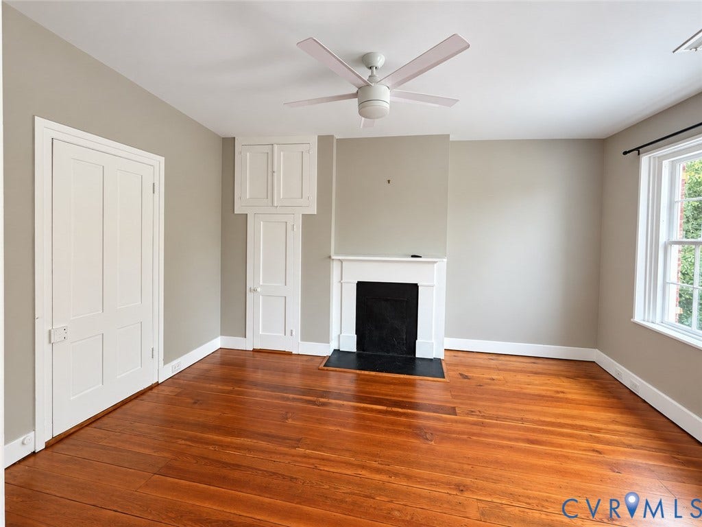 315 Grove Avenue, Petersburg, VA 23803 Hardwood flooring throughout, featuring a white ceiling fan, built-in cabinetry, and a fireplace with a white mantel and black hearth