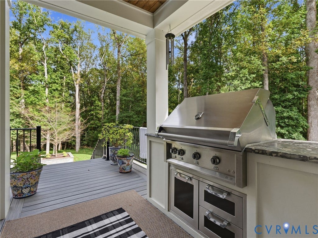 Outdoor kitchen with a built-in stainless steel grill, integrated storage, and a stone countertop