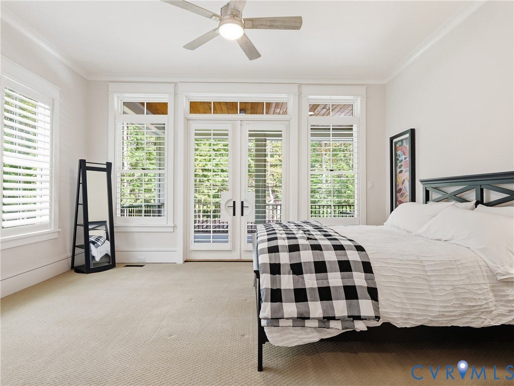 White plantation shutters, crown molding, double French doors, light-colored carpeting, and a ceiling fan with integrated lighting