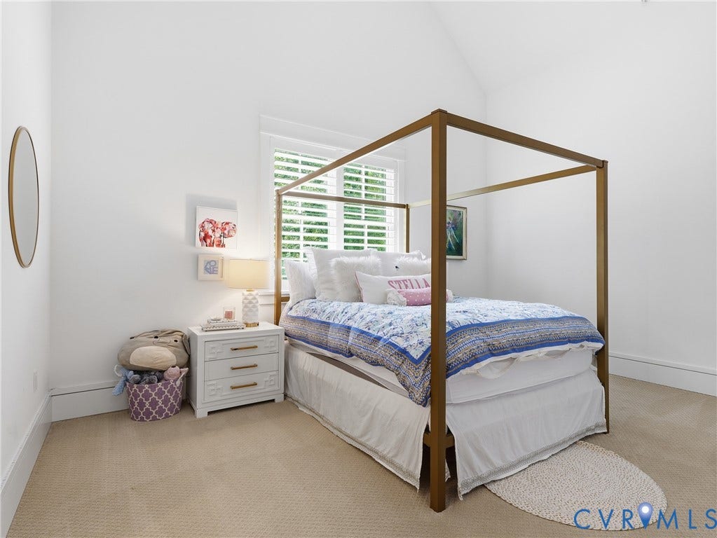 Vaulted ceiling, window with plantation shutters, light-colored wall-to-wall carpeting, and white baseboards