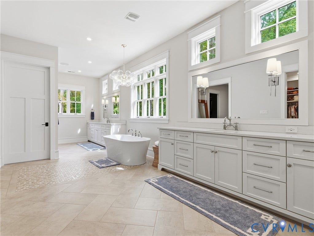 Spacious bathroom with dual vanities, freestanding soaking tub, and large format floor tiling