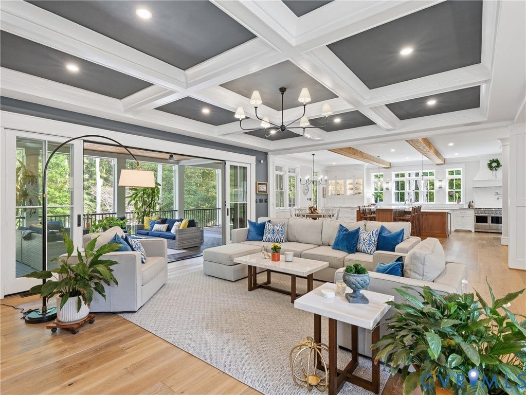 Coffered ceiling with recessed lighting, wide plank wood-finish flooring, sliding glass doors to outdoor living space, open-concept layout, and a contemporary chandelier