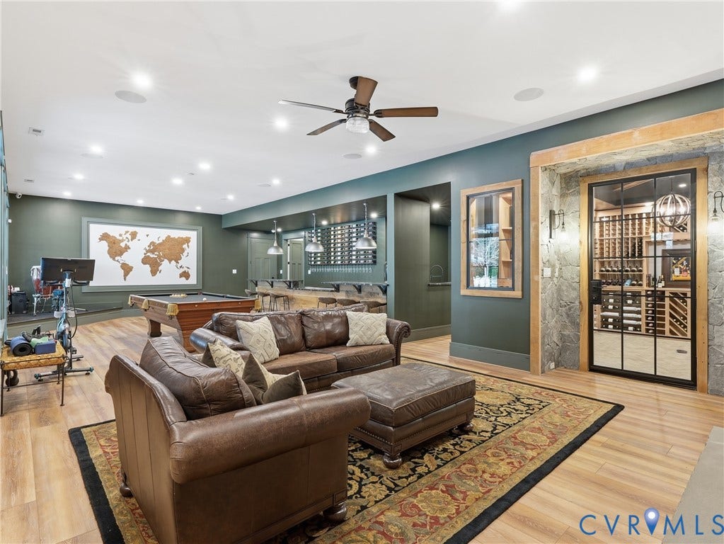 Expansive entertainment space featuring wood-finish flooring, recessed lighting, and a ceiling fan