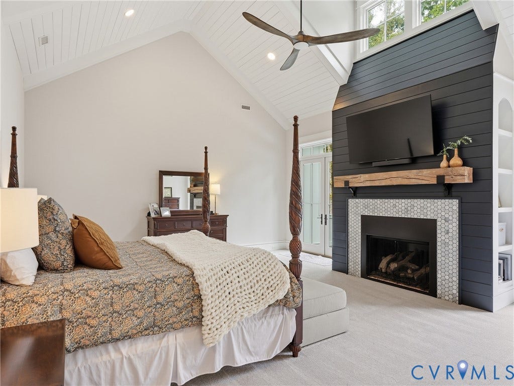Vaulted ceiling with white shiplap detail, ceiling fan, fireplace with hexagonal tile surround, wood mantel, and built-in shelving