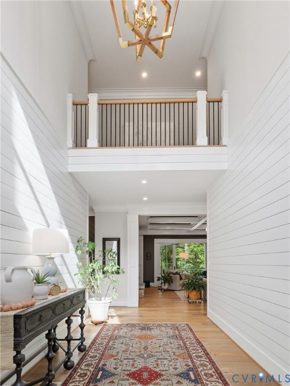 Two-story foyer featuring shiplap accent walls, a grand chandelier, and wood-finish flooring