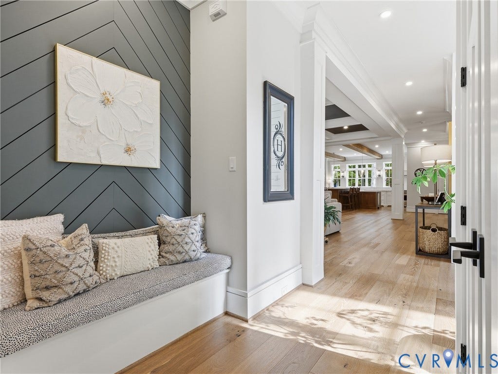 Built-in bench seating with cushion, chevron accent wall, wide plank wood-finish flooring, recessed lighting, and white trim molding