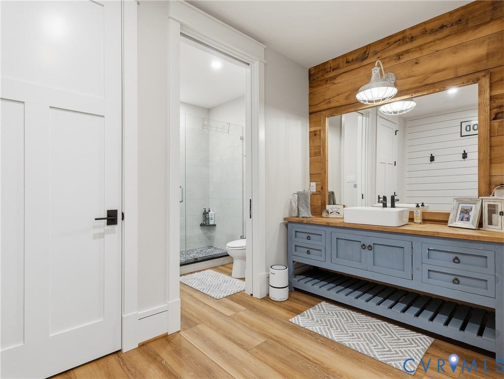 Wood-finish flooring with a blue vanity featuring storage drawers and open shelving
