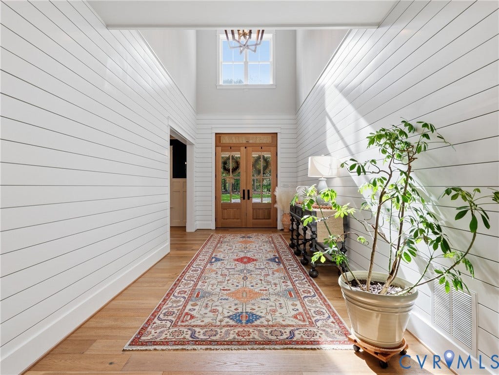 Two-story foyer featuring shiplap walls, wood-finish flooring, and a transom window