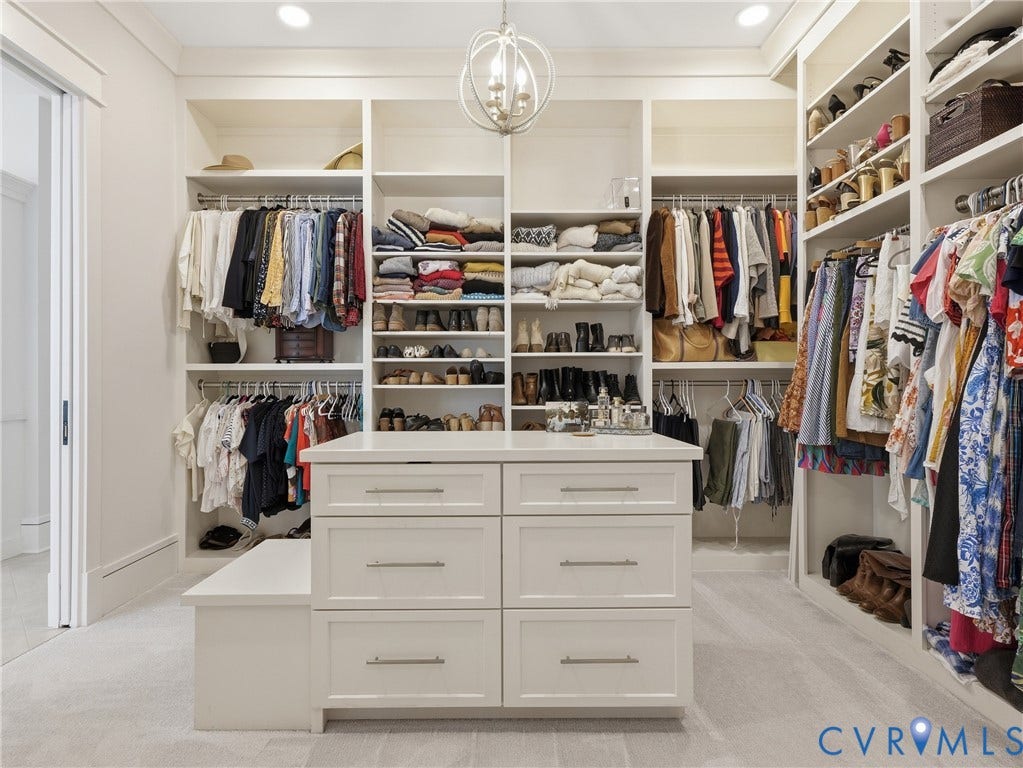 Built-in custom closet system with extensive shelving, hanging rods, and a central island with integrated drawers