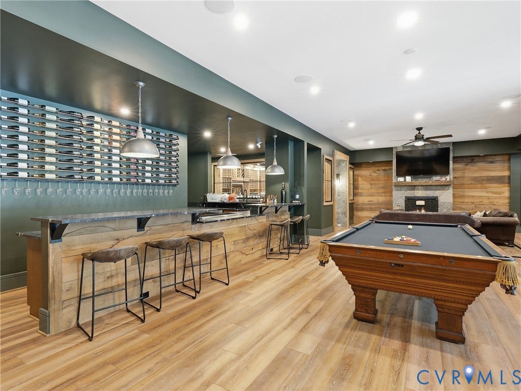 Wood-finish flooring, built-in bar, extensive wine storage, recessed lighting, and a stone-clad fireplace