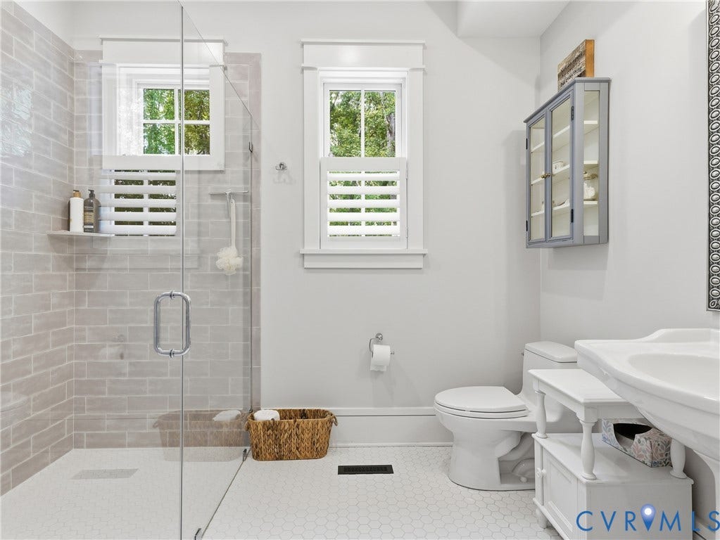 Glass-enclosed shower with subway tile surround, hexagonal floor tile, and built-in shower shelving