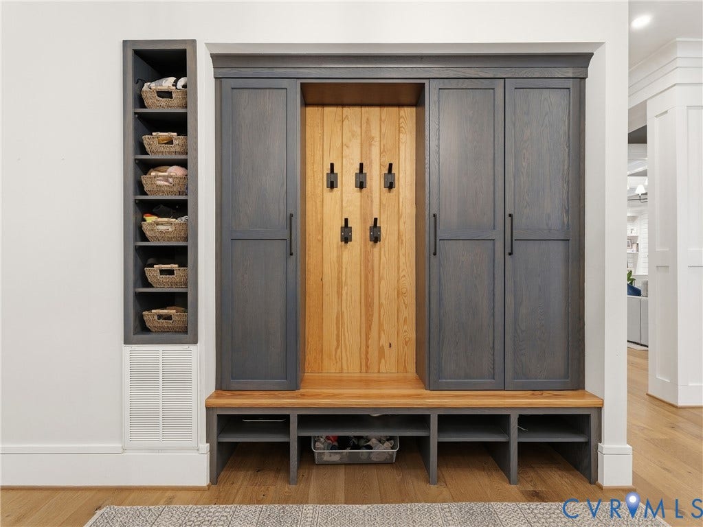 Built-in hall tree with dark wood-finish cabinetry, integrated bench seating, and wood-panel backing with black hardware