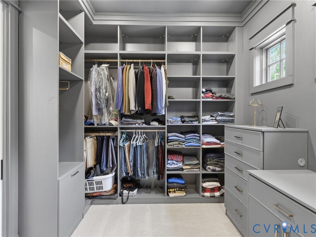 Custom closet system with extensive shelving, integrated hanging rods, built-in drawers, window, and crown molding