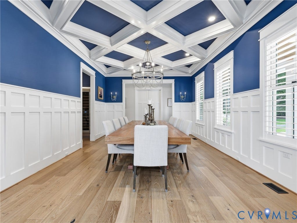 Coffered ceiling with recessed lighting, wood-finish flooring, white wainscoting, white plantation shutters, and a chandelier