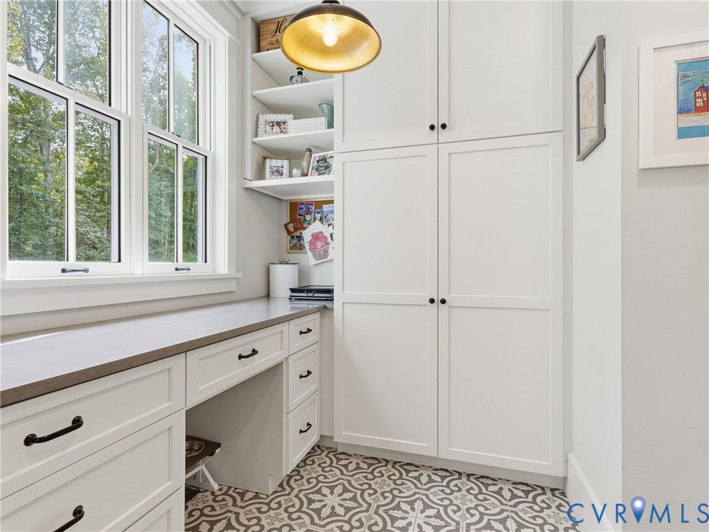 Built-in desk with solid surface countertop, custom cabinetry, open shelving, and patterned floor tile