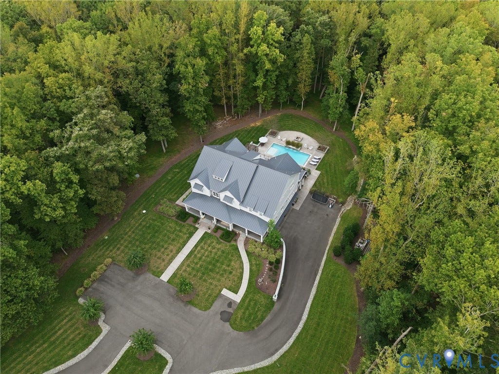 Expansive property featuring a private swimming pool, mature trees, a paved driveway, and a well-maintained lawn