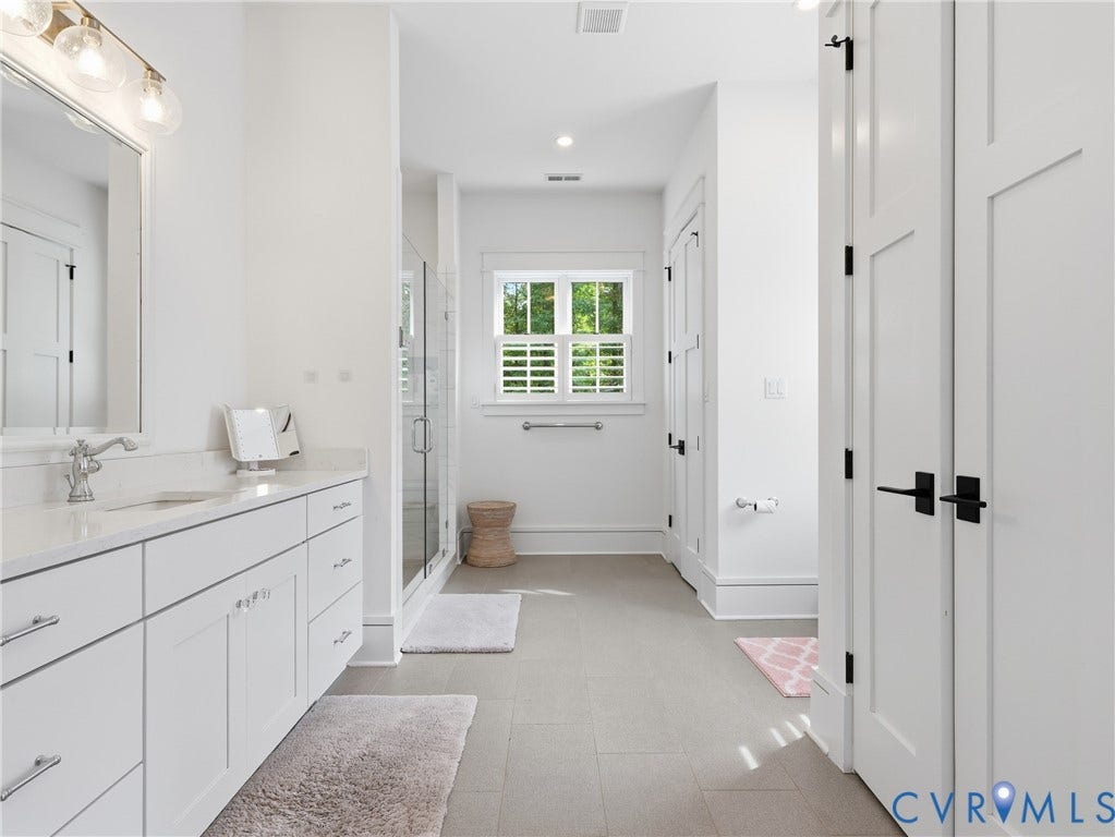 Dual sink vanity with white cabinetry, polished chrome hardware, and a light-colored countertop