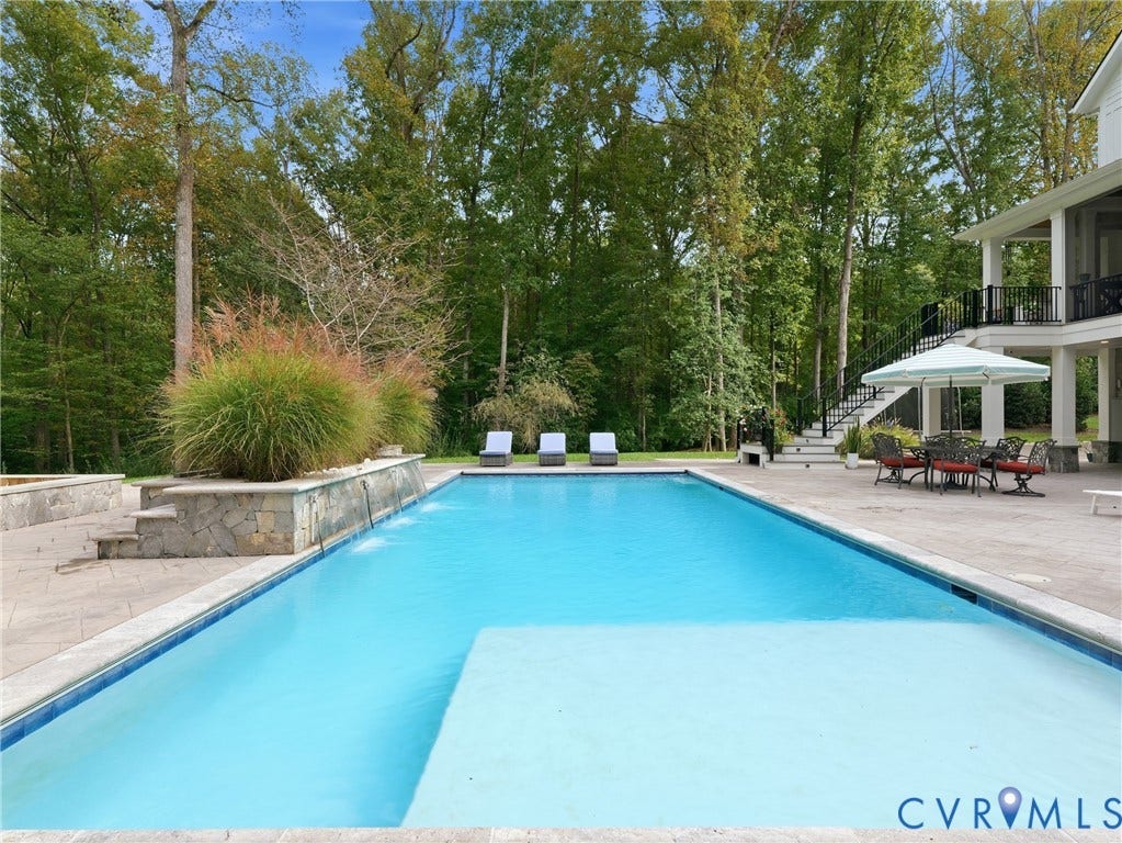 In-ground swimming pool with an integrated sun shelf, surrounded by a paved patio