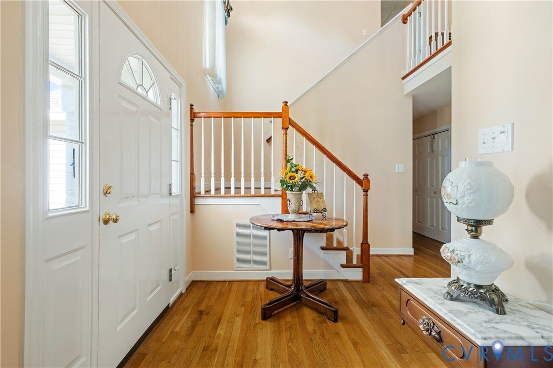717 McCauliff Drive, Chesterfield, VA 23236 Foyer featuring a white paneled entry door with an arched transom, sidelight windows, hardwood flooring, and a staircase with a wood handrail and white balusters