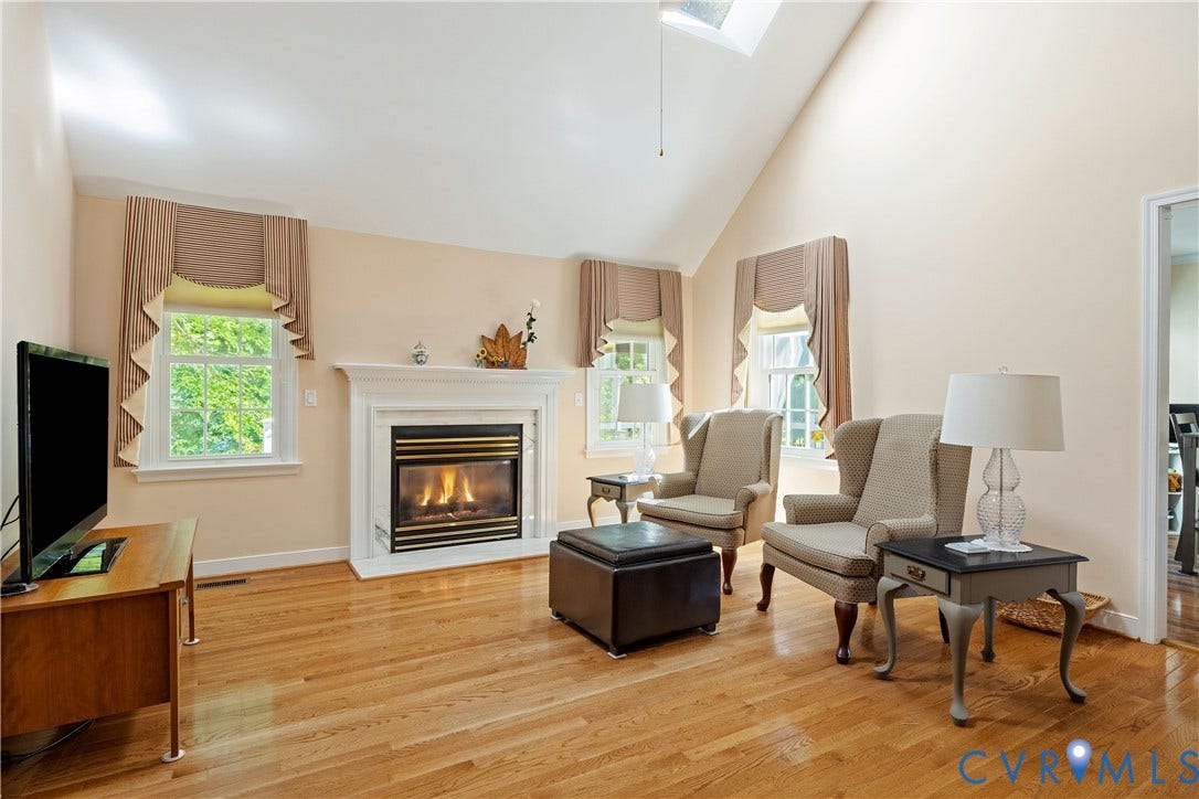 717 McCauliff Drive, Chesterfield, VA 23236 Vaulted ceiling with skylight, hardwood flooring, white window frames, and a fireplace with a white mantel