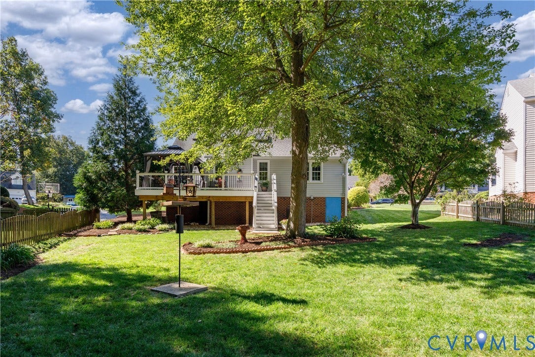 717 McCauliff Drive, Chesterfield, VA 23236 Expansive backyard with a manicured lawn, established trees, and a multi-level deck with white railings and stairs