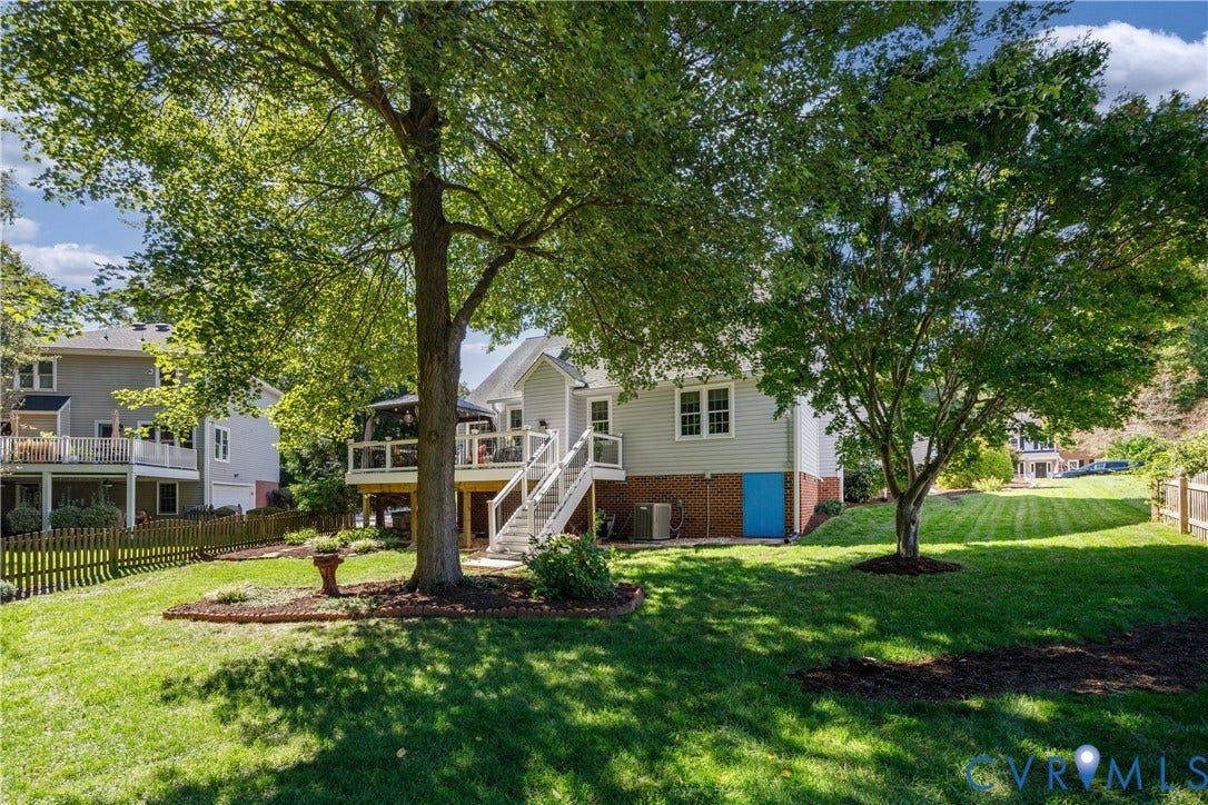 717 McCauliff Drive, Chesterfield, VA 23236 Expansive backyard featuring a manicured lawn, mature trees, wood privacy fence, and a deck with white railings