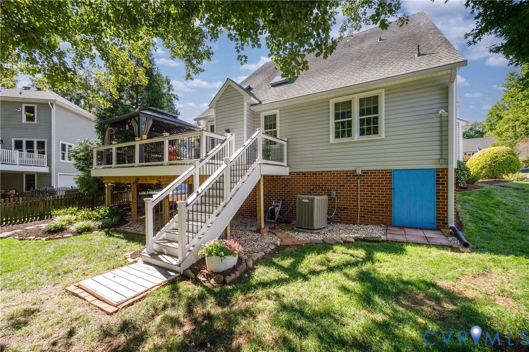 717 McCauliff Drive, Chesterfield, VA 23236 Rear exterior featuring a deck, white railing with black balusters, and a backyard with a sloped lawn