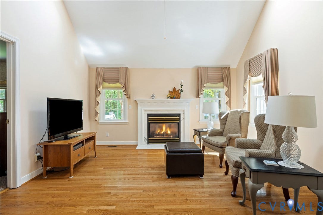 717 McCauliff Drive, Chesterfield, VA 23236 Vaulted ceiling, hardwood flooring, fireplace with a white mantel, and two windows providing natural illumination
