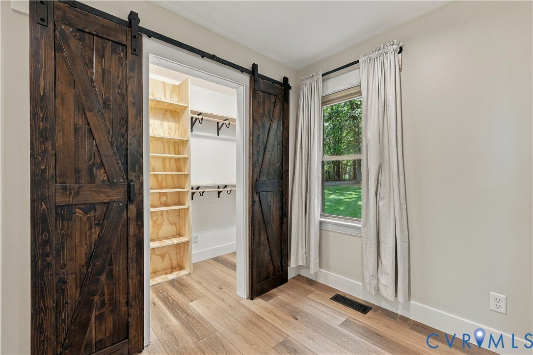 17 River Walk, Cumberland, VA 23027 Wood-finish flooring, two dark-stained barn doors, built-in shelving, white walls, and a window